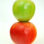Green apple on top of red apple