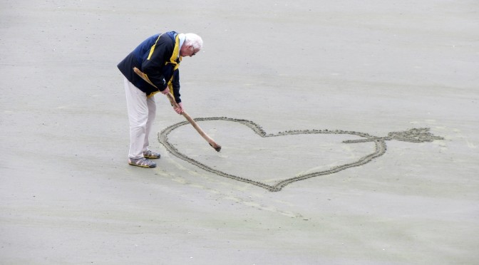 Man drawing heart shape in the sand
